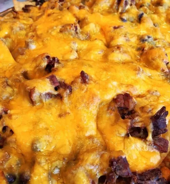 baked nachos with lots of melted cheese on a baking sheet