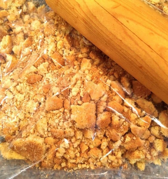 Coconut Cookies in a large zip lock bag being crushed by rolling pin