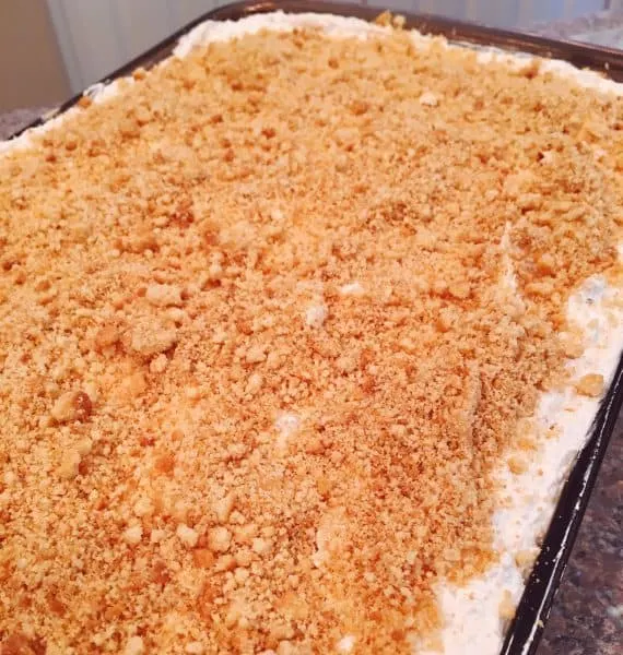 Coconut whipped cream topping spread over orange creamsicle dessert with cookie cream topping.