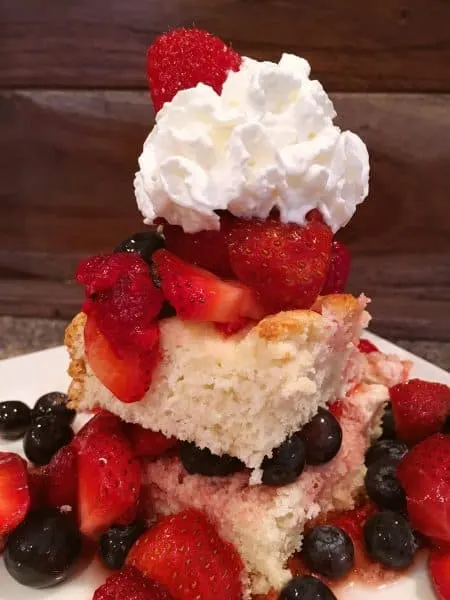 slice of cheesecake short bread topped off with fresh triple berries and whipped cream