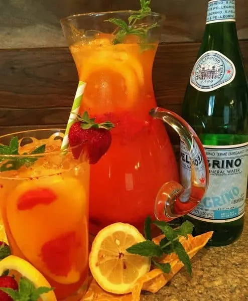 A glass and pitcher of Sparkling Strawberry Mango Lemonade
