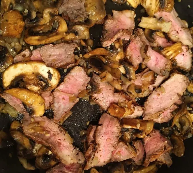 Adding left over sliced steak in with mushrooms and garlics