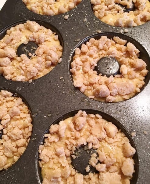 adding crumb topping to donut dough in baking pan