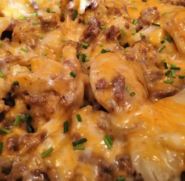 Close up photo of cooked potatoes and hamburger with melted cheese and diced chives.