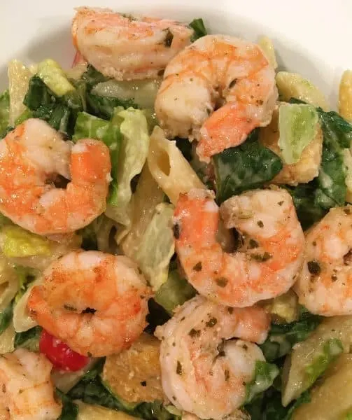 adding cooked shrimp to Caesar Salad.