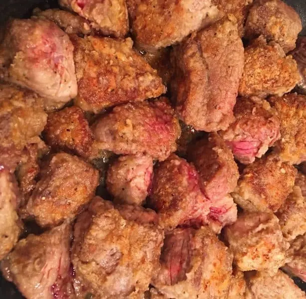 chunks of beef browned in a skillet 