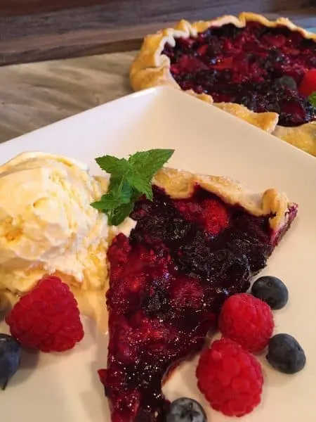 sliced of triple berry galette with vanilla ice cream scoop