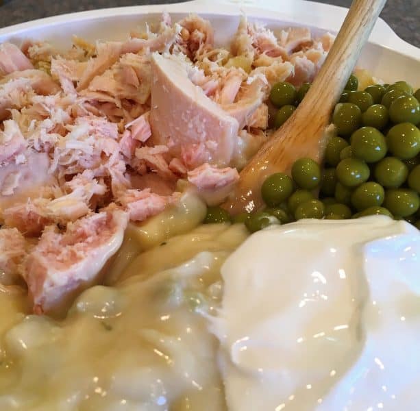 Mixing tuna, soups, peas, sour cream and pasta.