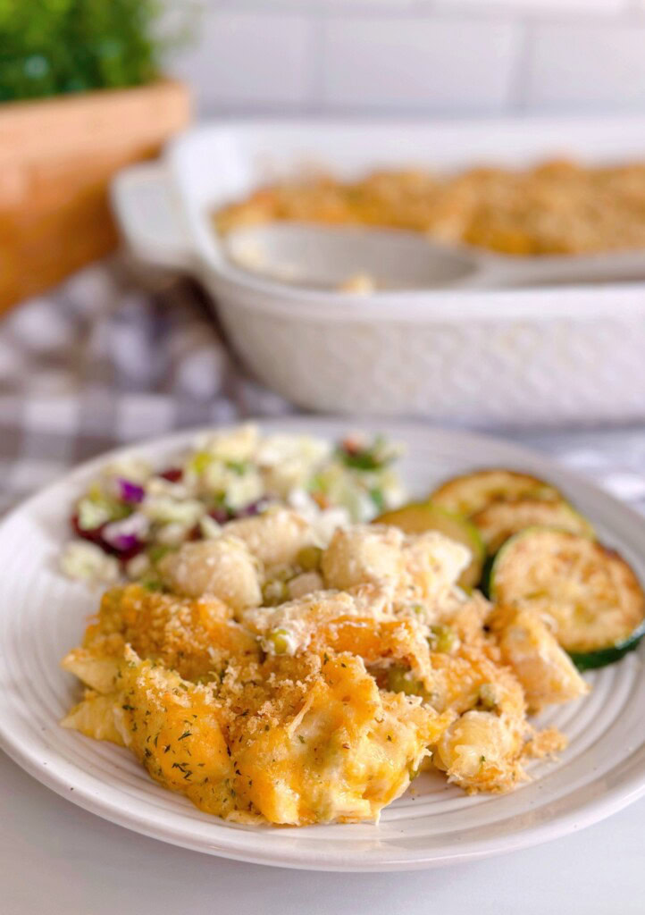 Tuna Noodle Casserole serving on a dinner plate with salad and veggies.
