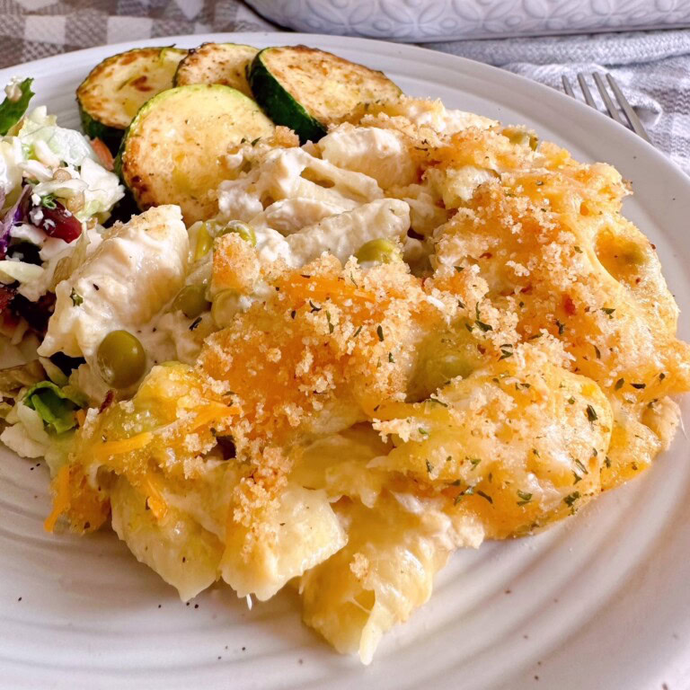 Tuna Noodle Casserole on a white dinner plate with vegetables.