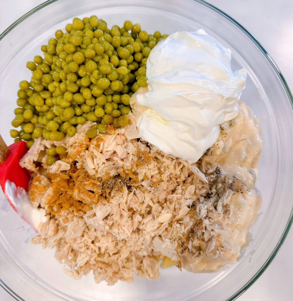Adding in the remaining ingredients for Tuna Noodle Casserole.