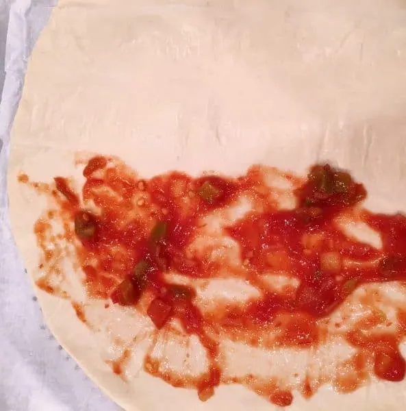 salsa spread on half of pizza crust