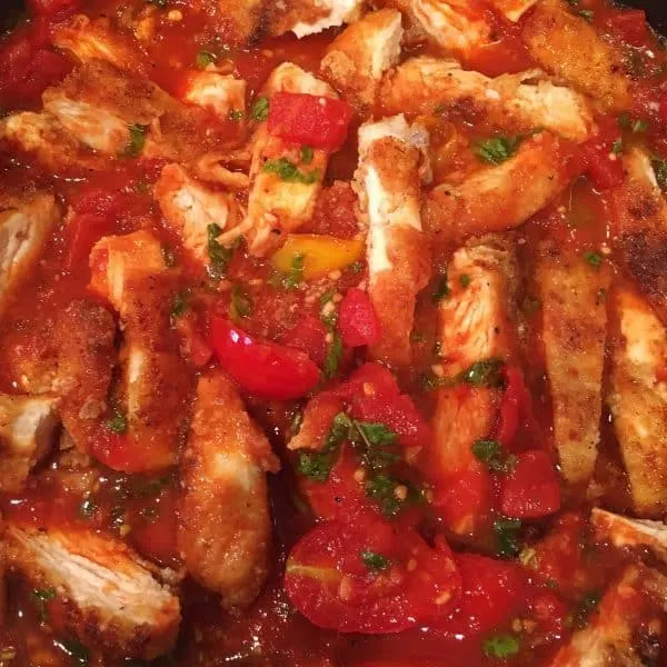 sliced chicken and tomato sauce in skillet