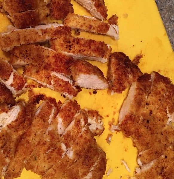 breaded and sliced chicken breast on cutting board