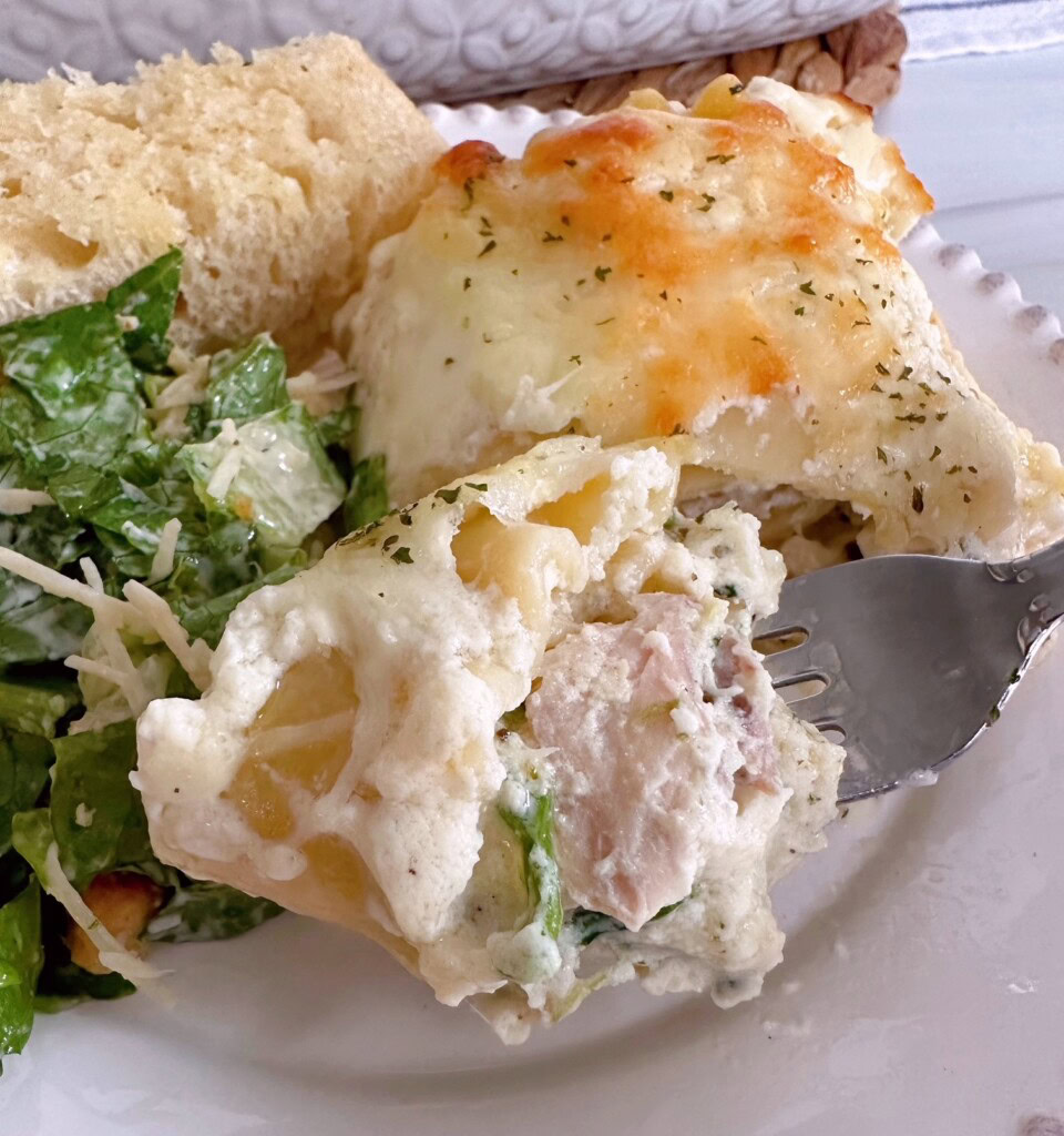 Forkful of chicken alfredo spinach roll-ups.