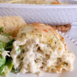 Spinach Alfredo Chicken Lasagna Roll up on a dinner plate with salad and garlic bread.