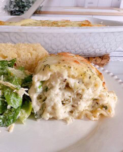 Serving of Chicken Alfredo Lasagna Roll Up on a dinner plate with salad and bread.