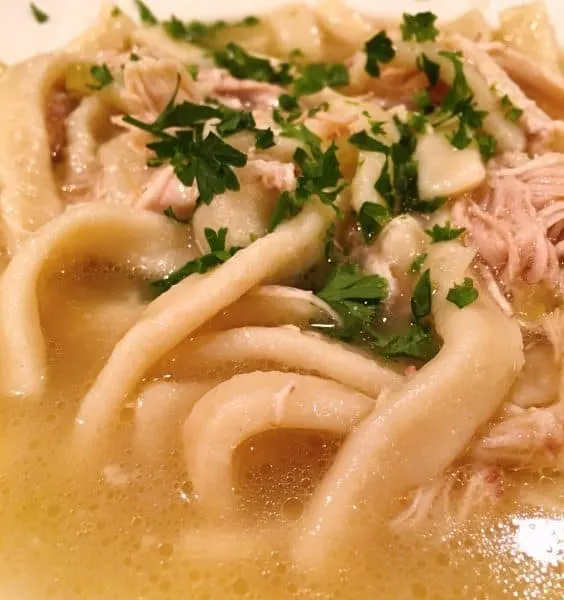 close up photo of chicken noodle soup with chopped parsley