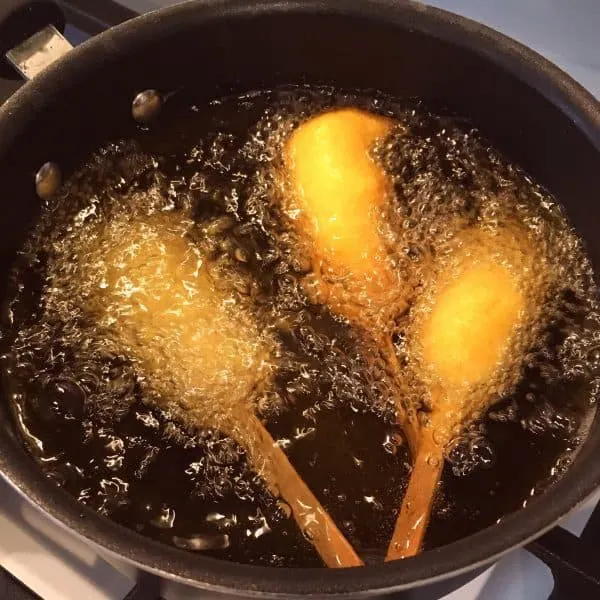 Corn dogs battered and frying in hot oil