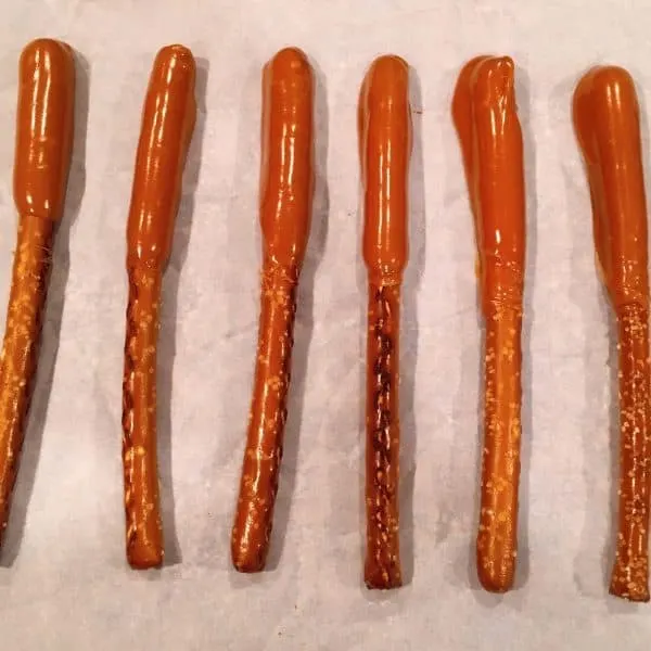 Pretzel Stick dipped in caramel and setting up on parchment paper