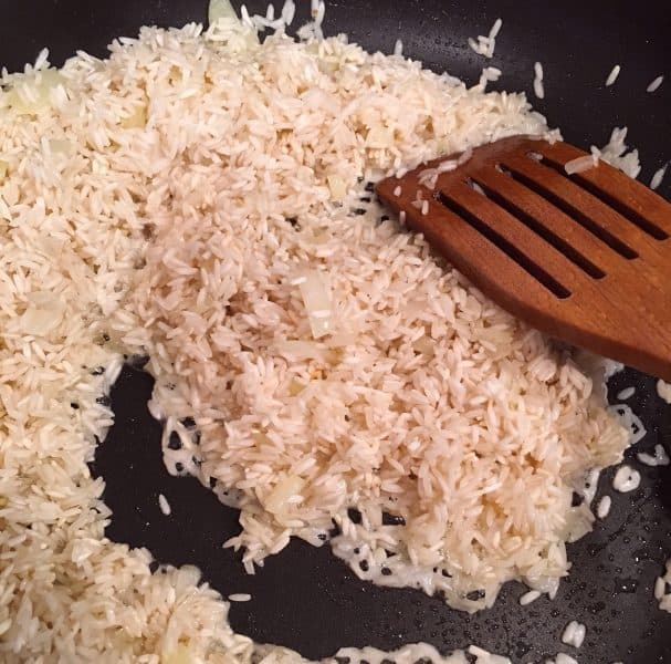 White rice frying in a hot skillet with onions
