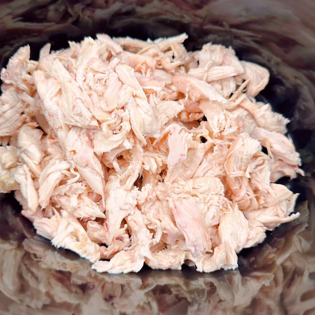 Shredded chicken in the bottom of the crock pot.