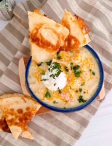Chicken Enchilada Soup in a soup bowl with a golden crispy cheese quesadilla.