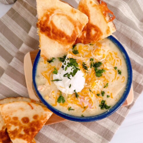 Chicken Enchilada Soup in a soup bowl with a golden crispy cheese quesadilla.