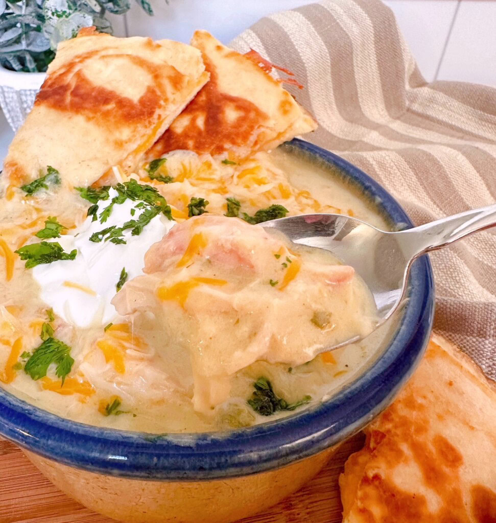 Chicken Enchilada Soup with a big spoonful hanging over the bowl of soup.
