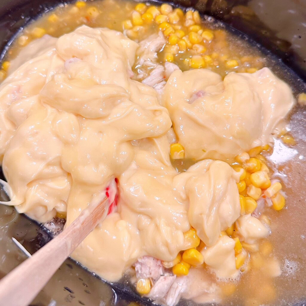 Adding liquids and corn to the soup.