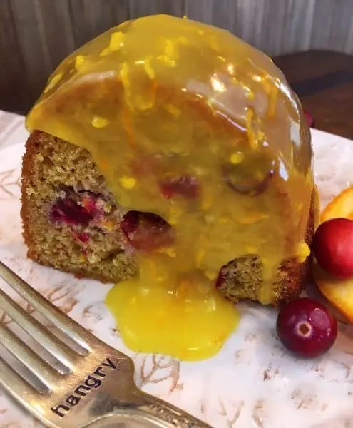 slice of cranberry orange cake with warm orange butter sauce