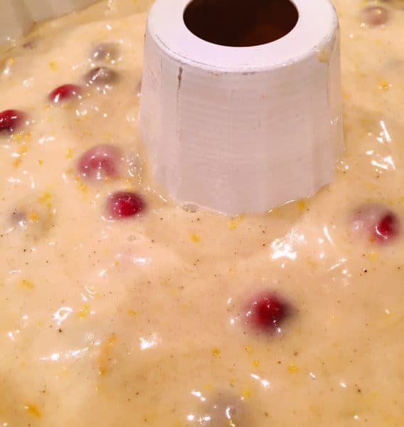 Adding Cranberry Orange cake batter in bundt cake pan to bake