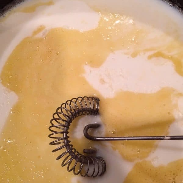 Adding flour and milk to butter to create a roux