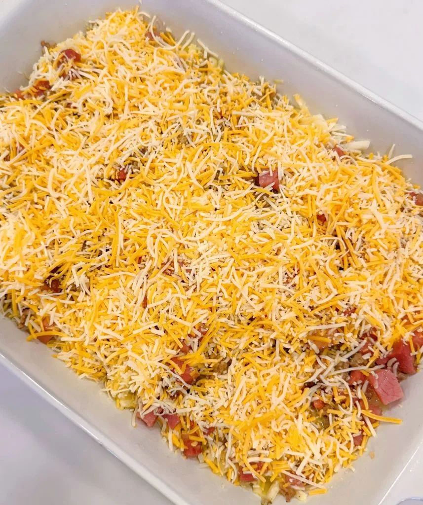 Breakfast casserole topped with shredded cheese.