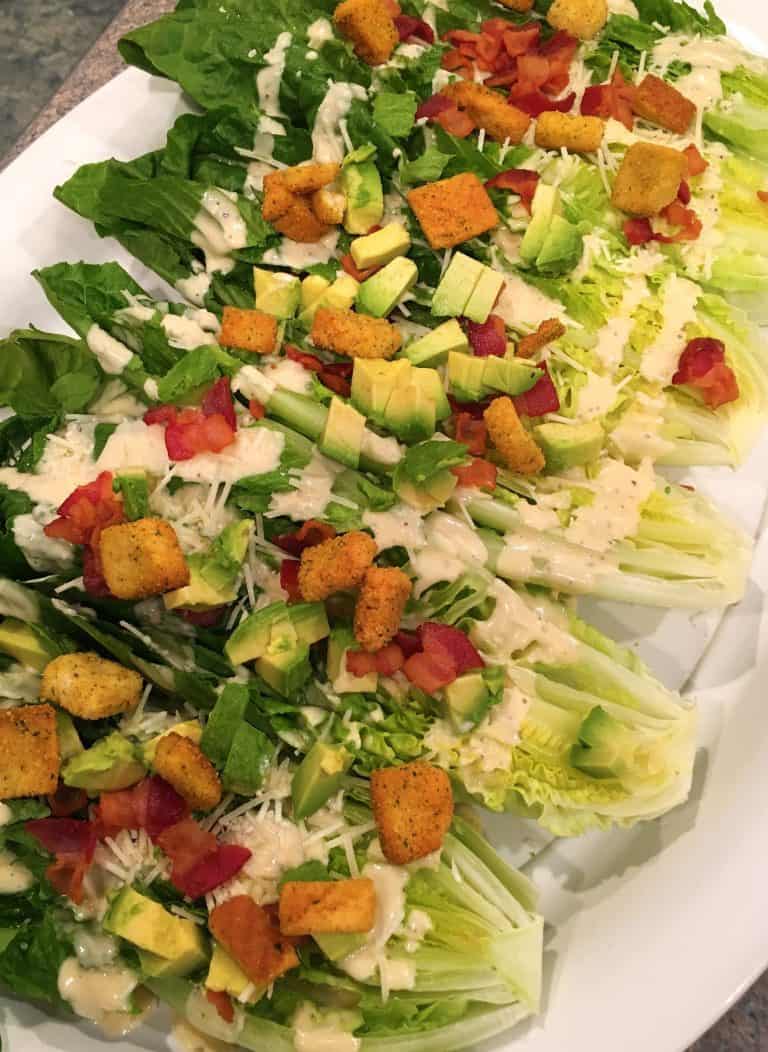 Cesar salad wedges on a white platter.