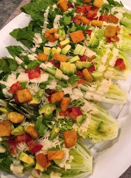 Romaine Lettuce heads cut in half and topped off with avocados, croutons, and cheese