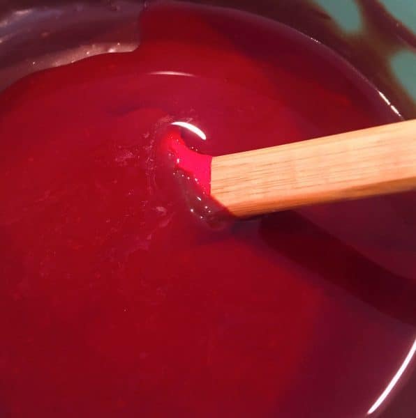 adding cherry juice to melted chocolate for topping over cherries