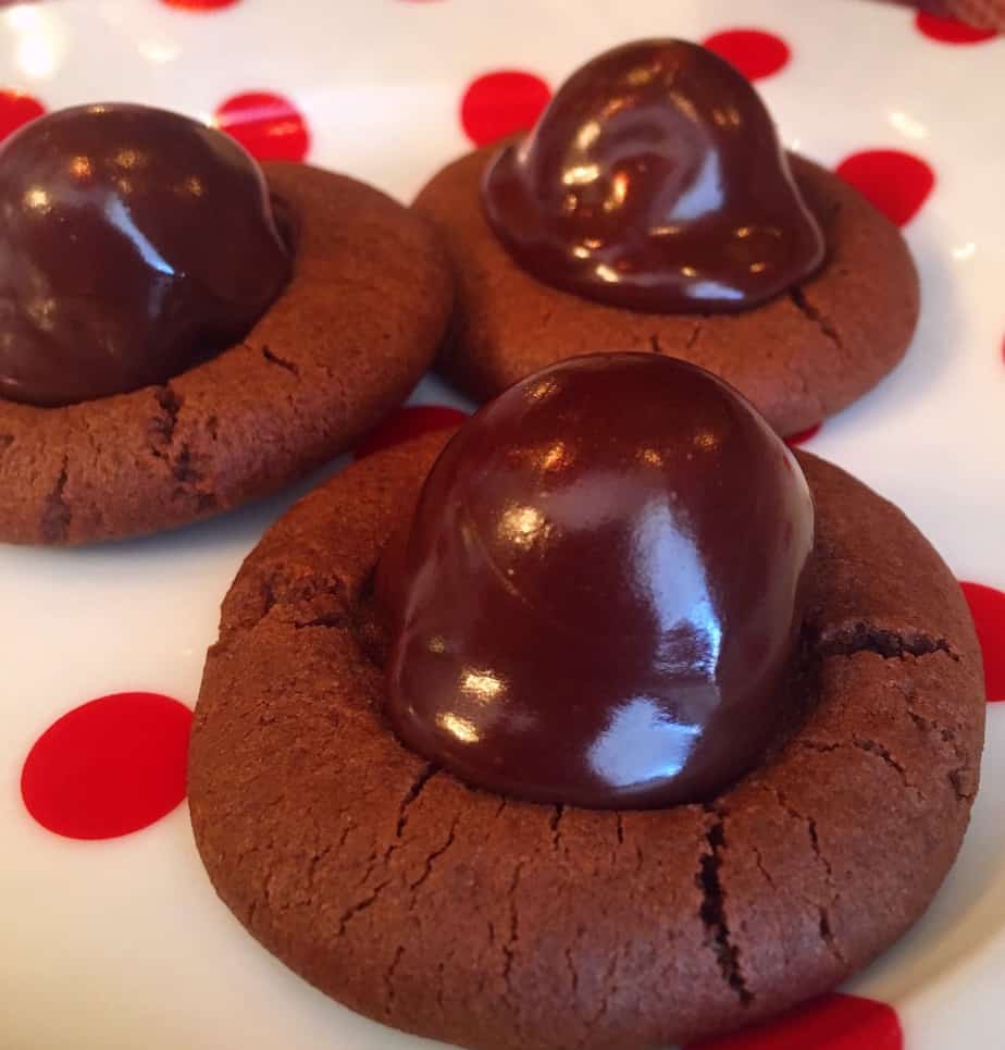 Chocolate cookies with a cherry in the middle and chocolate drizzled on top