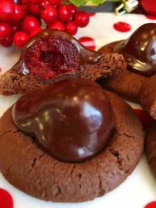 Chocolate Covered Cherry Cookies on a polka dot plate with one cut open to reveal the cherry under the chocolate glaze.