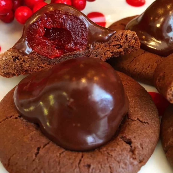 Chocolate Covered Cherry Cookies on a polka dot plate with one cut open to reveal the cherry under the chocolate glaze.