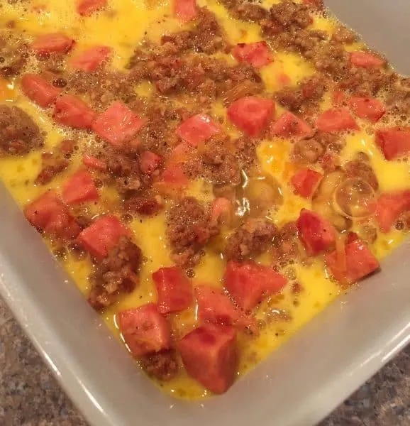 Eggs poured over potatoes and meat for breakfast casserole