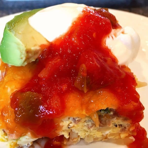 piece of breakfast casserole with salsa, sour cream, and avocado on top