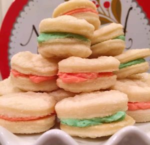 Stack of Christmas Creme Sandwich Cookies on a white cake plate.