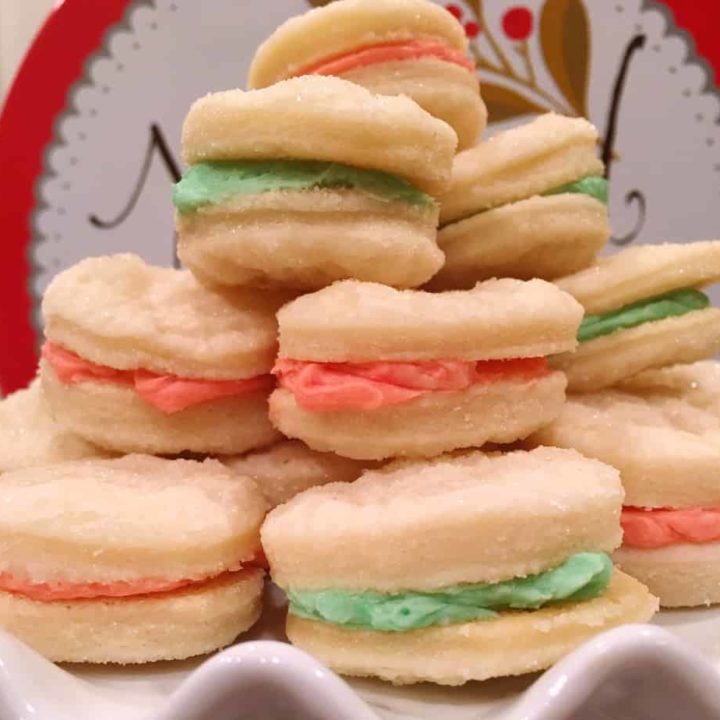Stack of Christmas Creme Sandwich Cookies on a white cake plate.