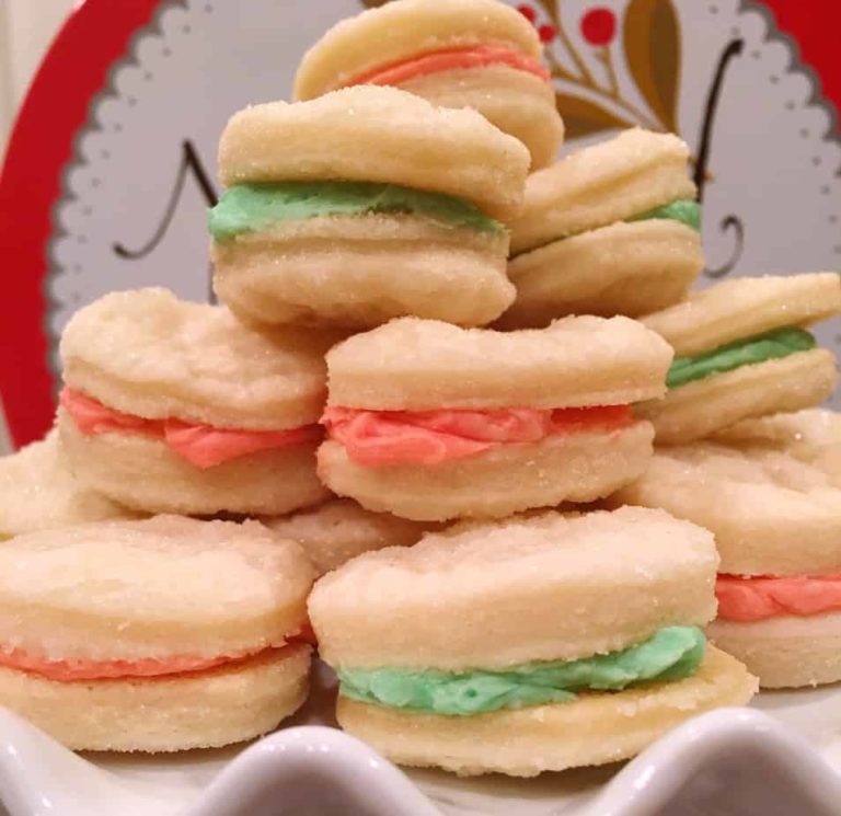 Stack of Christmas Creme Sandwich Cookies on a white cake plate.