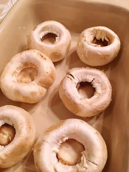 Mushroom caps in a small casserole dish ready to stuff