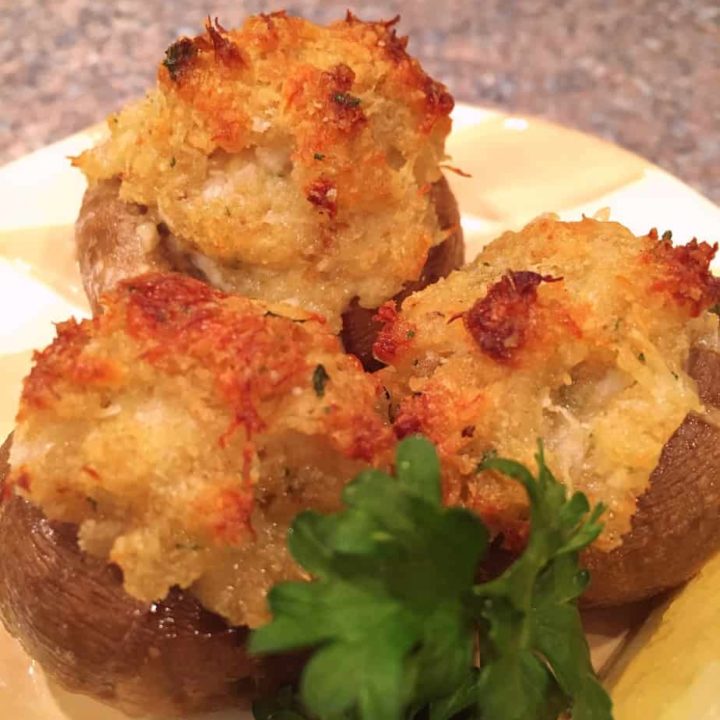 Crab stuffed mushrooms with parsley on a serving plate.