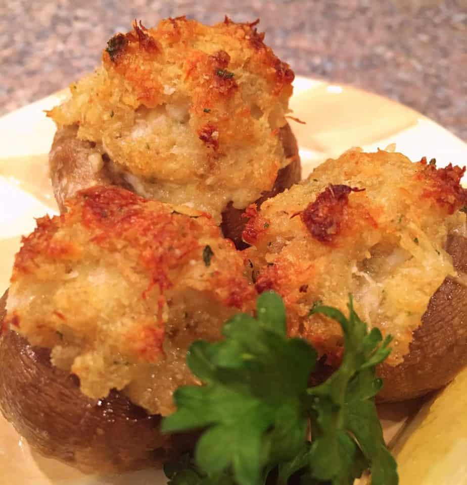 Crab stuffed mushrooms with parsley on a serving plate.