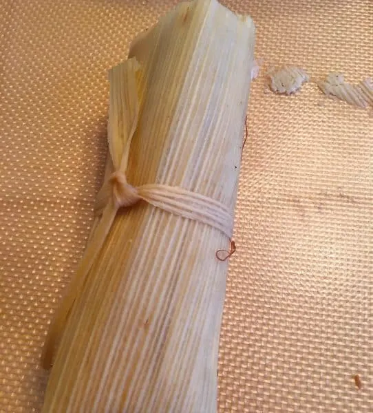 Tamale rolled up and tied off with husk bands