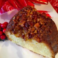 A delicious rum cake slice with nuts on top.